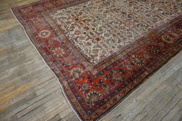 Traditional multicolor rug featuring an ivory field and red floral border on worn gray hardwood.
