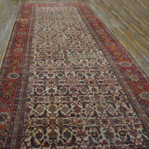 Detailed runner rug with a cream floral pattern and rust border lying on rustic wood flooring.