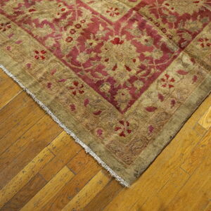 Red and khaki traditional rug with a floral pattern rests on diagonal distressed hardwood flooring.
