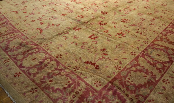 Low pile rug in faded khaki and deep red with a wide decorative floral border design.