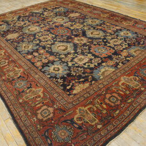 Traditional navy and rust rug with dense floral pattern rests on light wood plank flooring.
