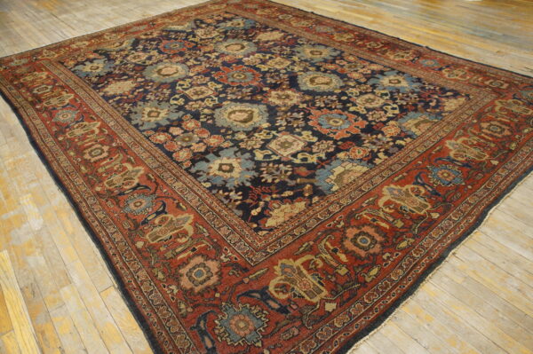 Traditional navy and rust rug with dense floral pattern rests on light wood plank flooring.
