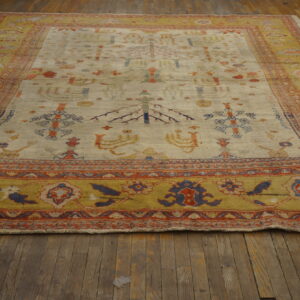 Cream rug with scattered tribal motifs and a wide mustard yellow border on distressed wood floors.