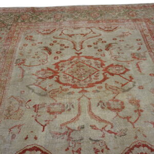 Low-pile rug with a large central red pattern on a faded beige and olive-toned traditional field.