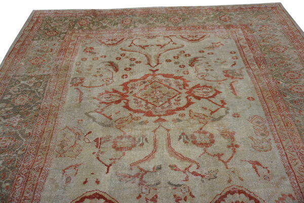 Low-pile rug with a large central red pattern on a faded beige and olive-toned traditional field.