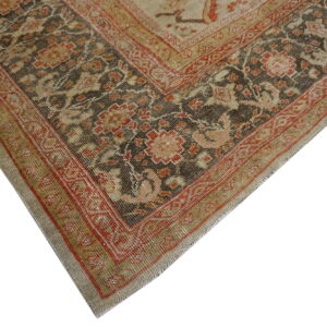 Close-up of a distressed rug corner showing dark brown, red, and beige traditional floral designs.