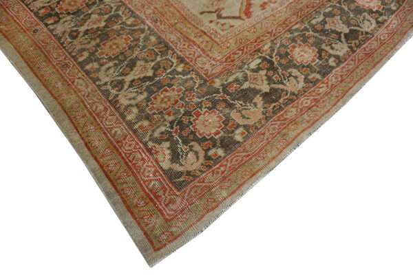 Close-up of a distressed rug corner showing dark brown, red, and beige traditional floral designs.