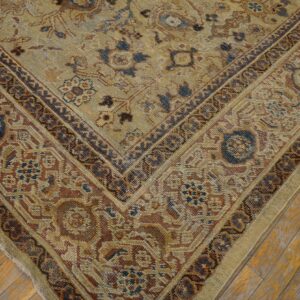 Intricate beige, rust, and blue patterned rug corner on distressed amber wood planks.