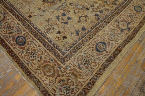 Intricate beige, rust, and blue patterned rug corner on distressed amber wood planks.