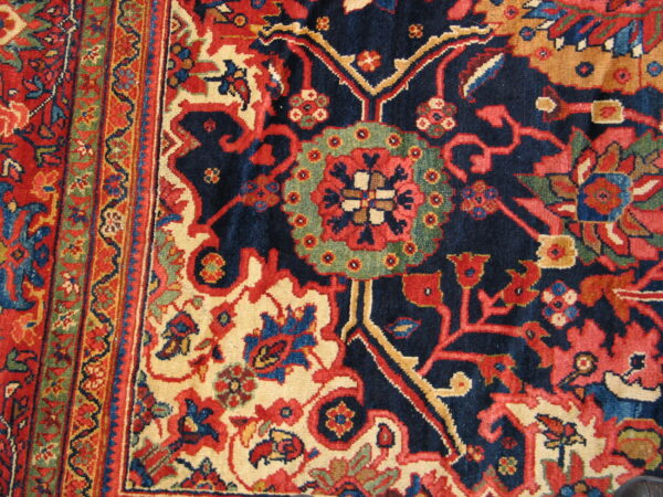 Intricate navy, red, cream, and green floral patterns cover the dense pile of this traditional rug.