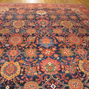 Navy and coral patterned rug with intricate floral designs covers a glossy hardwood floor.