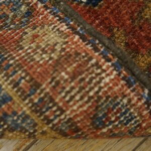 A close-up shows the flatwoven multicolored rug backing and the thick rust, gold, and brown pile on wood flooring.