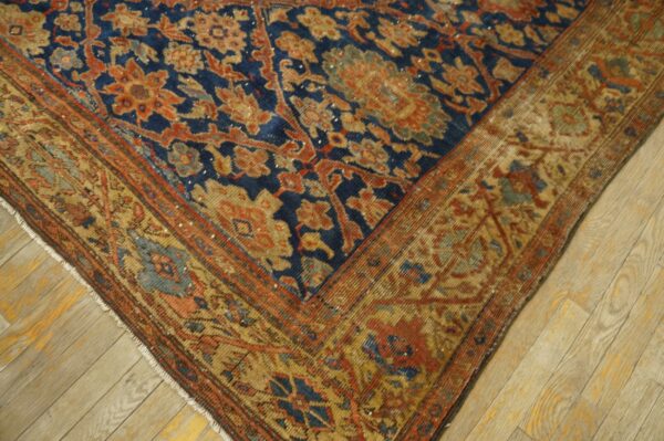 Ornate blue rug with floral patterns in orange and gold, resting on light wooden flooring.
