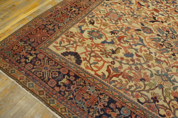 Low-pile rug featuring a cream field with floral vines and a dark navy border with geometric motifs on wood flooring.