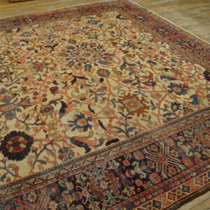 Multi-colored traditional rug with a light field and dark border laid over wood planks.