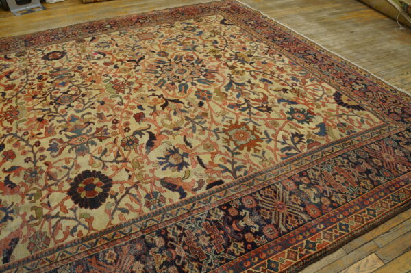 Multi-colored traditional rug with a light field and dark border laid over wood planks.