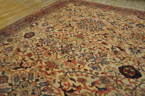 Traditional low-pile rug featuring a dense floral design in muted red, blue, and cream on a wood floor.