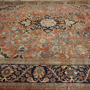 Faded traditional rug featuring a large navy and cream medallion on a distressed terracotta field, resting on wood flooring.