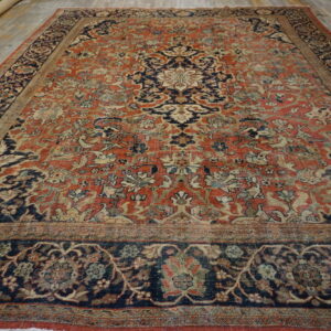 Ornate medallion rug featuring faded terracotta, navy, and cream colors, displayed on light wooden floorboards.