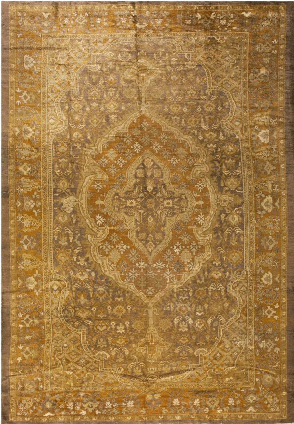 Elaborate traditional area rug with a large gold and brown ornamental medallion and borders.