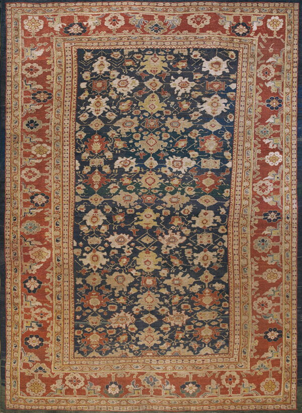 Traditional blue rug with densely patterned floral motifs and a prominent red-orange multiple border.