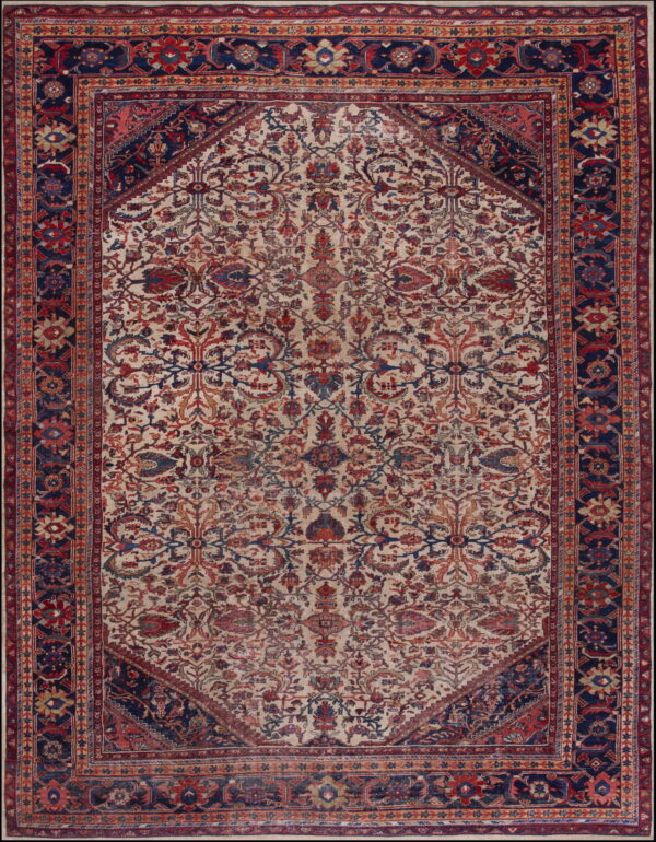 Cream rug with an elaborate red and blue floral pattern, framed by dark navy spandrels and border.