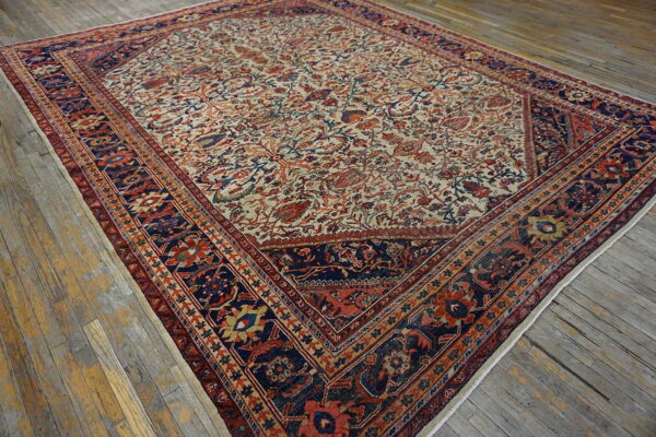 Traditional cream rug with a dense all-over floral pattern and multi-layered navy and red border on wood.