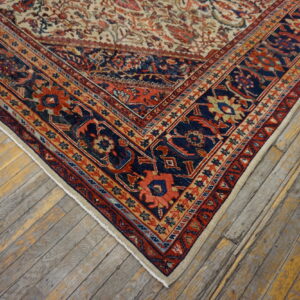 Corner view of a traditional navy, red, and beige patterned rug resting on distressed hardwood floors.