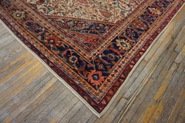 Corner view of a traditional navy, red, and beige patterned rug resting on distressed hardwood floors.