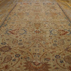 Low-pile beige rug with complex traditional rust and blue pattern rests on distressed wooden planks.