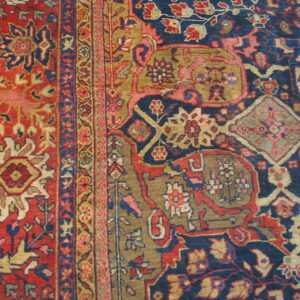 Close-up of a traditional rug featuring complex floral and geometric motifs in red, navy blue, and khaki.
