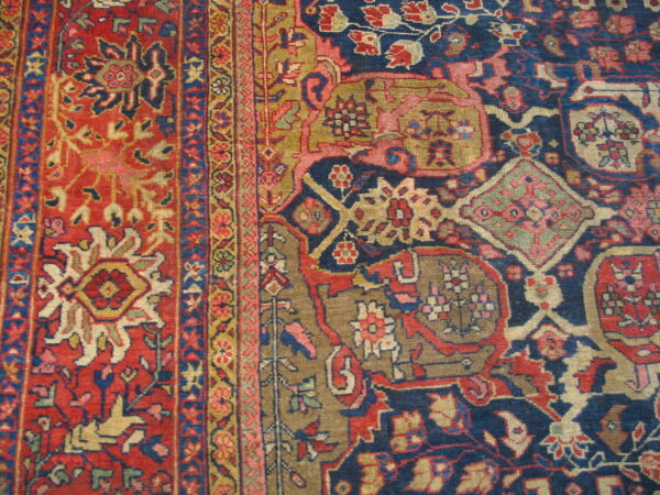 Close-up of a traditional rug featuring complex floral and geometric motifs in red, navy blue, and khaki.