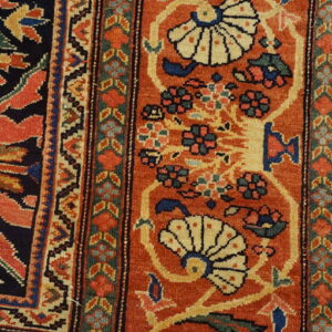 Detailed low-pile rug section in rust, navy, cream, and green with traditional floral and geometric patterns.