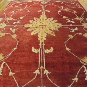 Red rug with a golden central medallion and scrolling cream floral patterns on a wood floor.