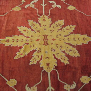 Deep red rug detail with a large golden medallion and stylized foliage pattern on a striated field.
