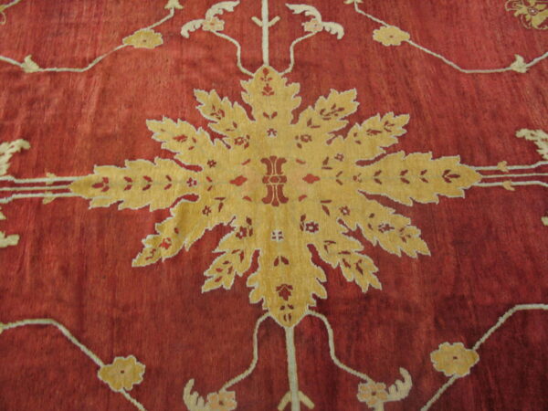 Deep red rug detail with a large golden medallion and stylized foliage pattern on a striated field.