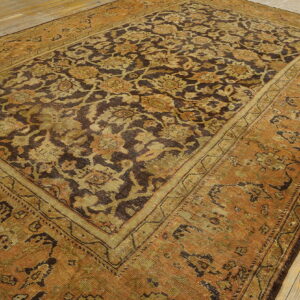 Rust-toned rug with a dense dark brown and olive green floral pattern on distressed wood flooring.