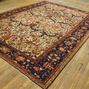 Low-pile rug with a detailed cream, rust, and navy floral pattern displayed on distressed wood planks.