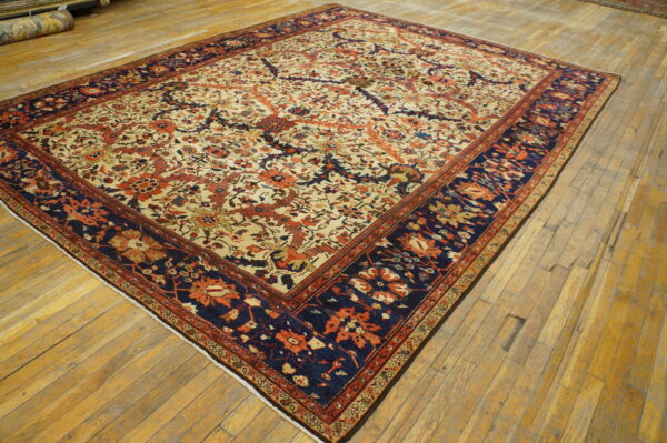 Low-pile rug with a detailed cream, rust, and navy floral pattern displayed on distressed wood planks.