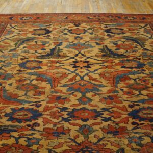 Traditional floral rug with gold, rust, and navy blue colors covers light plank flooring.