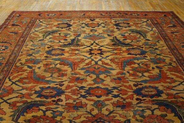 Traditional floral rug with gold, rust, and navy blue colors covers light plank flooring.