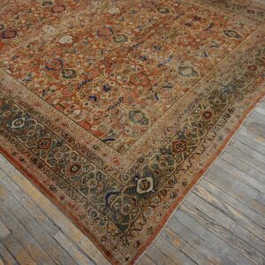 Ornate orange and faded olive rug corner resting on weathered plank hardwood floorboards.