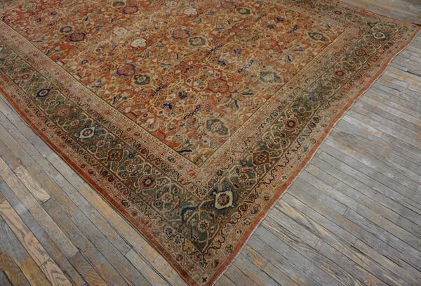 Ornate orange and faded olive rug corner resting on weathered plank hardwood floorboards.