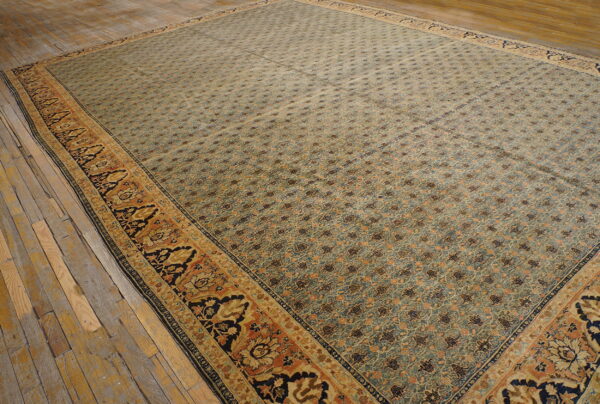 Large patterned rug in blue, rust, and gold with an ornate border lies on rustic wooden flooring.