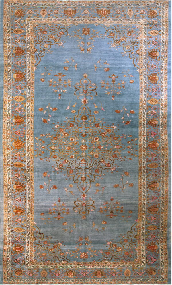 Azure rug with visible sheen, detailed floral motifs in gold, rust, and pink, surrounded by a wide border.
