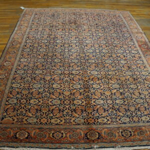 Large navy and terracotta traditional area rug featuring an all-over pattern, displayed on wood floors.