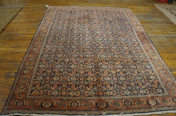 Large navy and terracotta traditional area rug featuring an all-over pattern, displayed on wood floors.