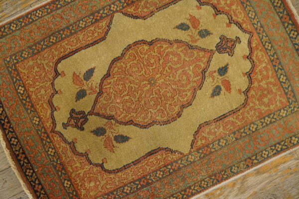Low pile rug featuring a rust medallion on a golden tan field, framed by complex blue and green borders.