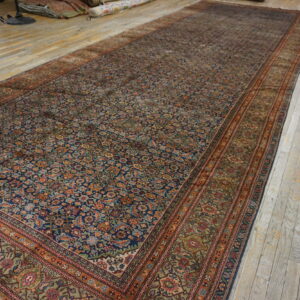 Large navy blue and rust area rug with dense traditional patterns covers distressed wooden flooring.