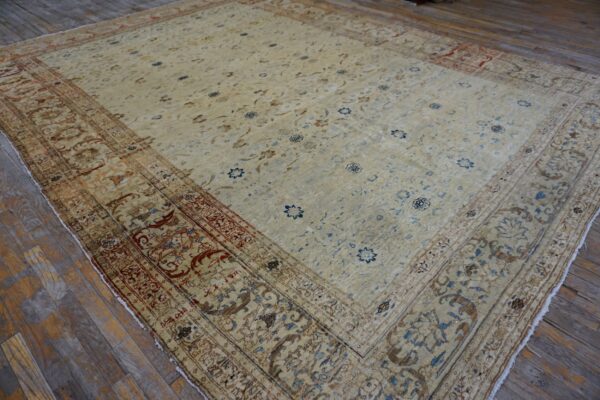 Low-pile beige traditional rug featuring blue and rust floral motifs on distressed wood planks.